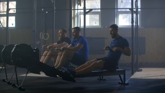 Fitness friends training on row ergometer machine at cross gym