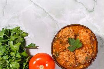 Meatballs with tomato sauce and parsley on marble background. Keto diet food. Ketogenic.