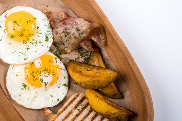 Fried eggs with bacon, potatoes and bread for breakfast