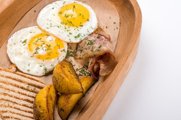 Fried eggs with bacon, potatoes and bread for breakfast
