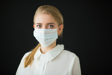 beautiful young woman in medical mask on a black background