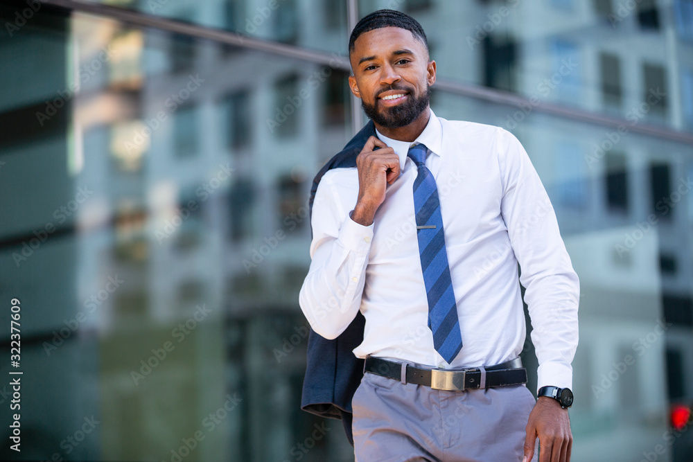 Wall mural Modern fashionable african american business man portrait in urban city, walking to work in financial district