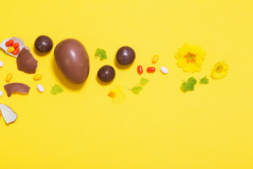 Easter yellow background with chocolatte eggs,    candy and spri