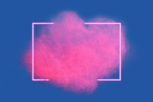 Pink neon powder explosion with gliwing frame on blue background. Colored cloud. Colorful dust explode. Paint Holi.