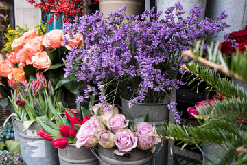 Bouquets of pink roses and red tulips, green hydrangea in pastel colors in large zinc buckets for sale in store.