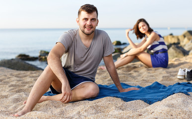 Man sitting on the beach. Girl on the background