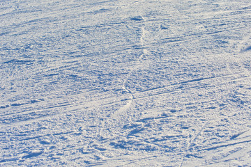 Groomed snowy ski slope with trace from skis and snowboards at sun winter day. Low depth of field. Selective focus