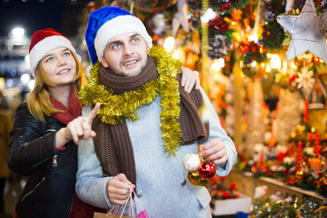 Couple in hat  at Christmas Fair, girl points to decorations