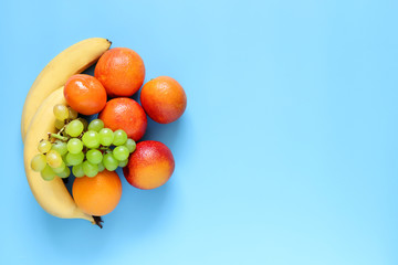 Oranges, bananas and grapes on blue background. Healthy and fresh fruits.