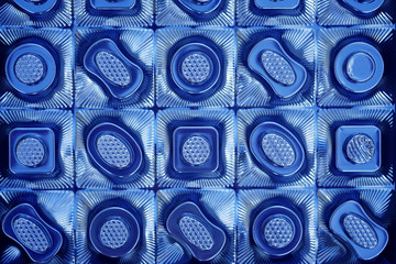 The texture of the plastic packaging of chocolates top view. Empty candy box background in blue.