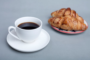 cup of coffee and croissant on wooden table