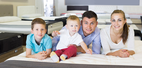  parents with two young sons testing mattress in store