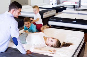 Obraz premium Girl with her family testing quality of mattress