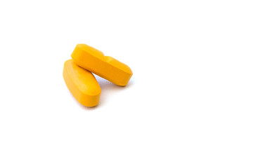 Close up side view of two orange pills which are isolated over the white background. A cure of diseases symbol. Health and medical treatment concept.