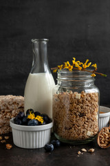 Ready breakfast – granola, muesli with fresh ripe blueberry, honey, multigrain cakes, white chocolate and milk. Close-up, useful product, background.