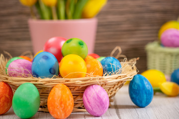 Fototapeta na wymiar Beautiful group Easter eggs in the spring of easter day, red eggs, blue, purple and yellow in Wooden basket with tulips on the wood table background