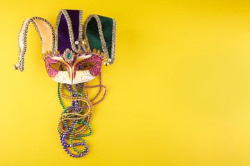 A festive, colorful mardi gras or carnivale mask on a yellow background. Venetian masks. - obrazy, fototapety, plakaty