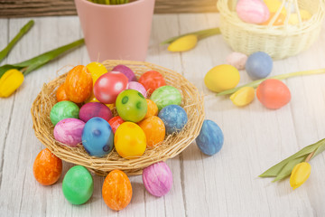 Fototapeta na wymiar Beautiful group Easter eggs in the spring of easter day, red eggs, blue, purple and yellow in Wooden basket with tulips on the wood table background