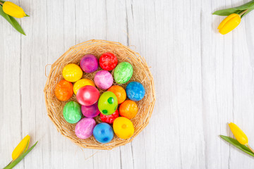 Obraz na płótnie Canvas Beautiful group Easter eggs in the spring of easter day, red eggs, blue, purple and yellow in Wooden basket with tulips on the wood table background