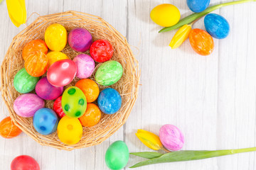 Beautiful group Easter eggs in the spring of easter day, red eggs, blue, purple and yellow in Wooden basket with tulips on the  wood table background
