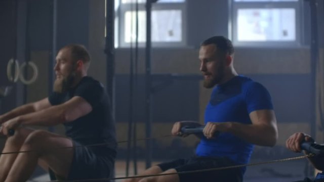 Fitness friends training on row ergometer machine at cross gym