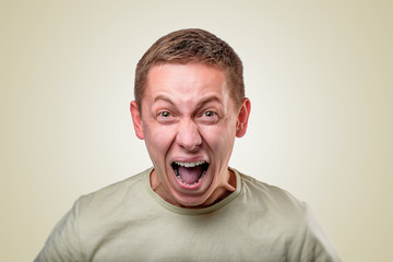 An angry young man screams on a yellow background.