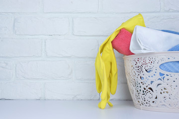 basket with towels and rubber gloves for cleaning on the table on a brick background