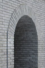 Fototapeta na wymiar Brick gray wall with a semicircular arch entrance.