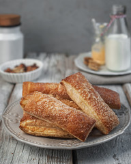 food photography of puff pastry with sugar covering with bottles of milk on a light gray texture background