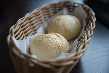 Two sesame buns are in the bread basket. Bread close-up.