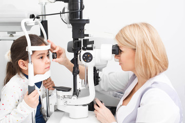 Optometrist examines retina of a girl’s patient’s eye with special ophthalmic equipment in a modern clinic. Vision correction in children