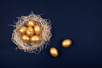 Top view of golden colored Easter eggs in decorative nest on dark blue background. Happy Easter...
