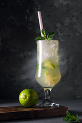 Refreshing lime cocktail with mint and ice on a dark background. Soft drink with lime and mint. Close-up.