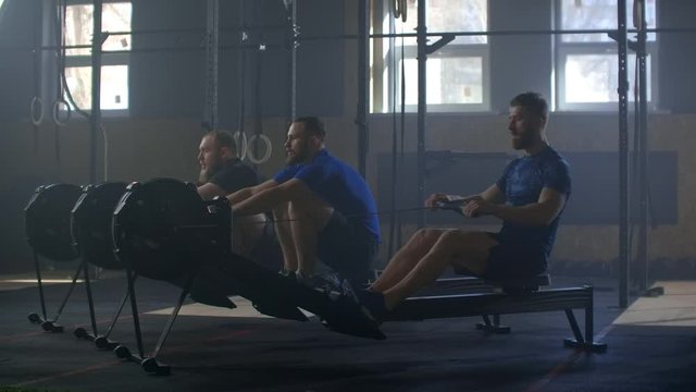 Slow motion: Fitness friends training on row ergometer machine at cross gym