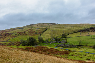 A scenic view of a mountain farm building with grassy slope under a grey sky