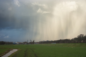 Hail and snow fall streaks of a wintry shower over the dutch landscape