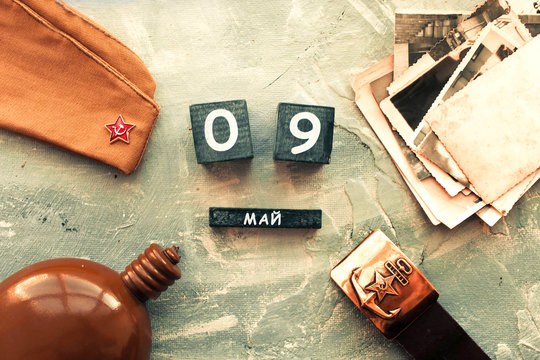 Flask, cap, soldier belt with a five-pointed star with a hammer and sickle. old photographs of the war years and a wooden calendar with the date May 09.  Victory Day