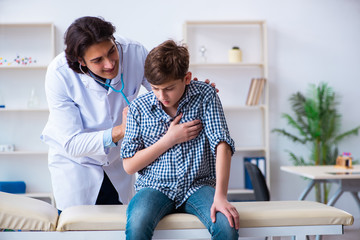 Fototapeta premium Male doctor examining boy by stethoscope