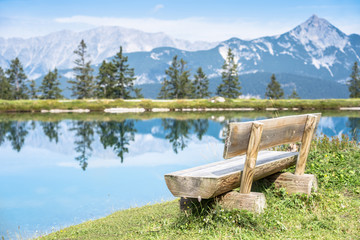 Mountain lake landscape view with bench in foreground