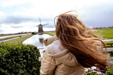 Girl with long red hair developing in the wind. Woman looking into the distance at a typical Dutch...