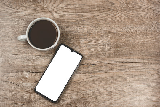 Phone and coffee on a vintage wooden background. Technology concept background. White screen phone copy space.