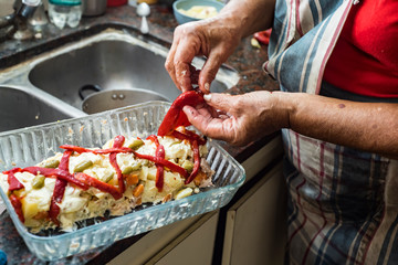 older woman preparing russian salad with mayonnaise potatoes bell peppers and olives