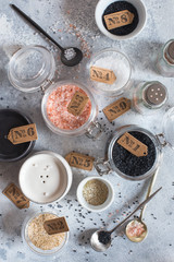 Mix of different salt types on grey concrete background. Sea salts, black and pink Himalayan salt crystals, powder. collection of different types of salt. Top view flat lay. Different Sea salts