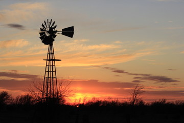 Kansas colorful Sunset with cloud's,tree's and a Windmill silhouette out in the country.