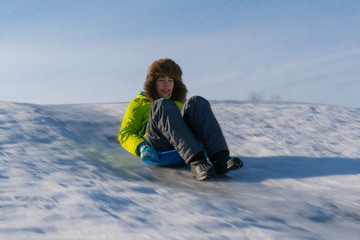 Fototapeta na wymiar Joyful boy rides on an ice slide