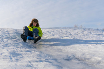 Fototapeta na wymiar Cheerful boy slides down the ice slide