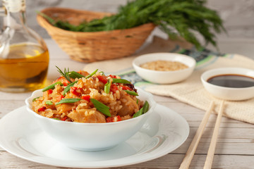 Tori chahan fried Japanese rice with vegetables and chicken in soy sauce in a black plate on a wooden table