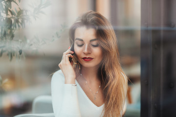 girl talking on phone seen through the window