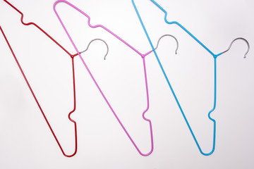 Many colorful metal wire coat, clothes hangers on white background