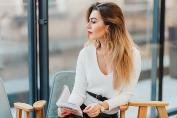 The girl with a book in hand look through the window. Profile shot